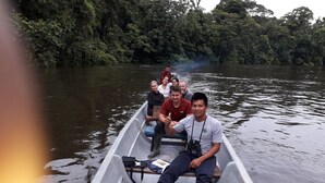 A small boat with four people on a calm river surrounded by dense greenery. - Alojamiento y tour en la Amazonia (Lago agrio)