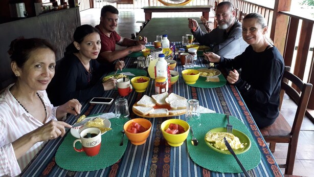 A group of people dining at a table with a variety of dishes, including bread, fruit, and condiments. - Alojamiento y tour en la Amazonia (Lago agrio)