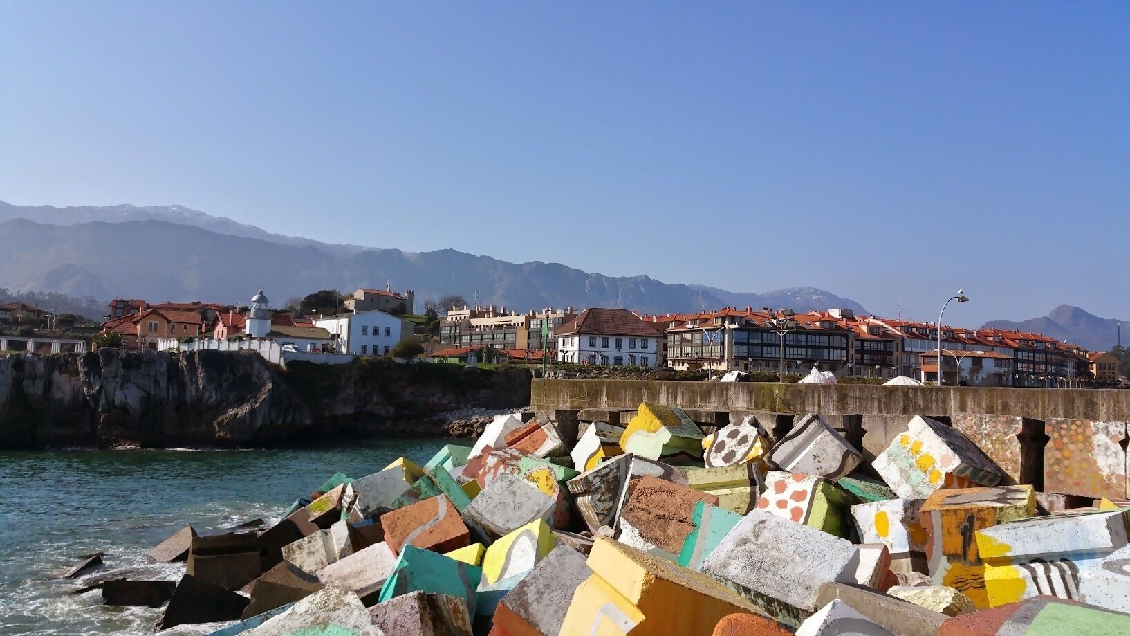 A coastal town with colorful buildings and a rocky shoreline.