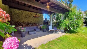 Un patio al aire libre con paredes de piedra, una zona de estar integrada y un hogar para la chimenea.