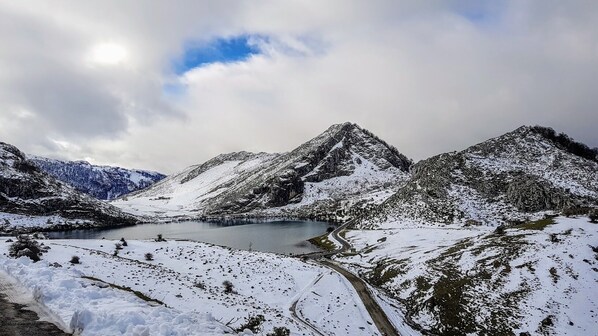 A snow-covered mountainous landscape with a lake and a winding road. - Holiday home Carmen (Llanes)