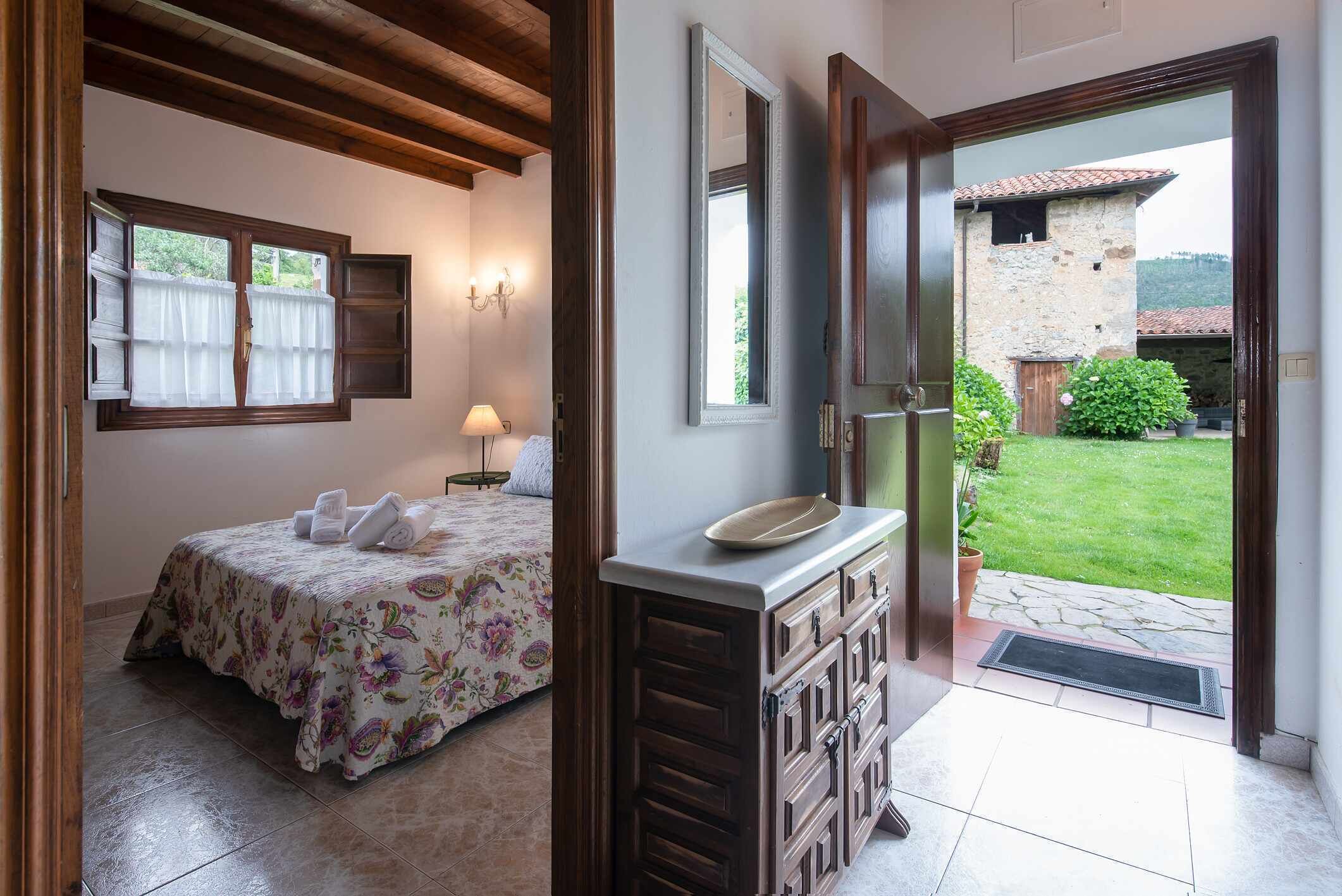 Une chambre à coucher avec un lit, une table de chevet, un miroir et une vue sur l’extérieur.