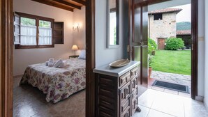 Un dormitorio con cama, mesita de noche, espejo y vistas al exterior.