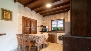 Una cocina con una mesa y sillas de madera, una lavadora y un microondas.