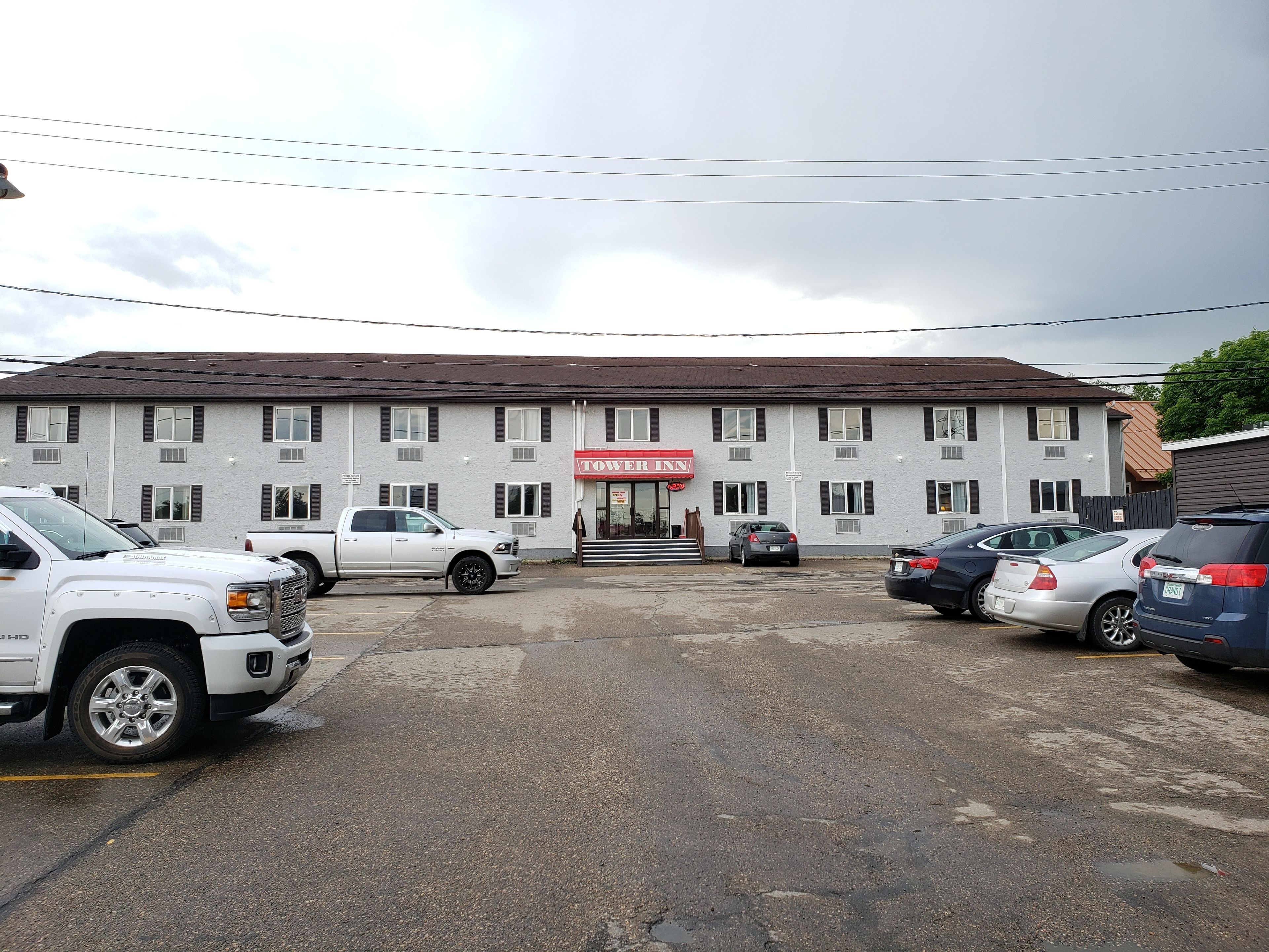 A motel with a sign reading "TOWER INN" and several parked cars in front.
