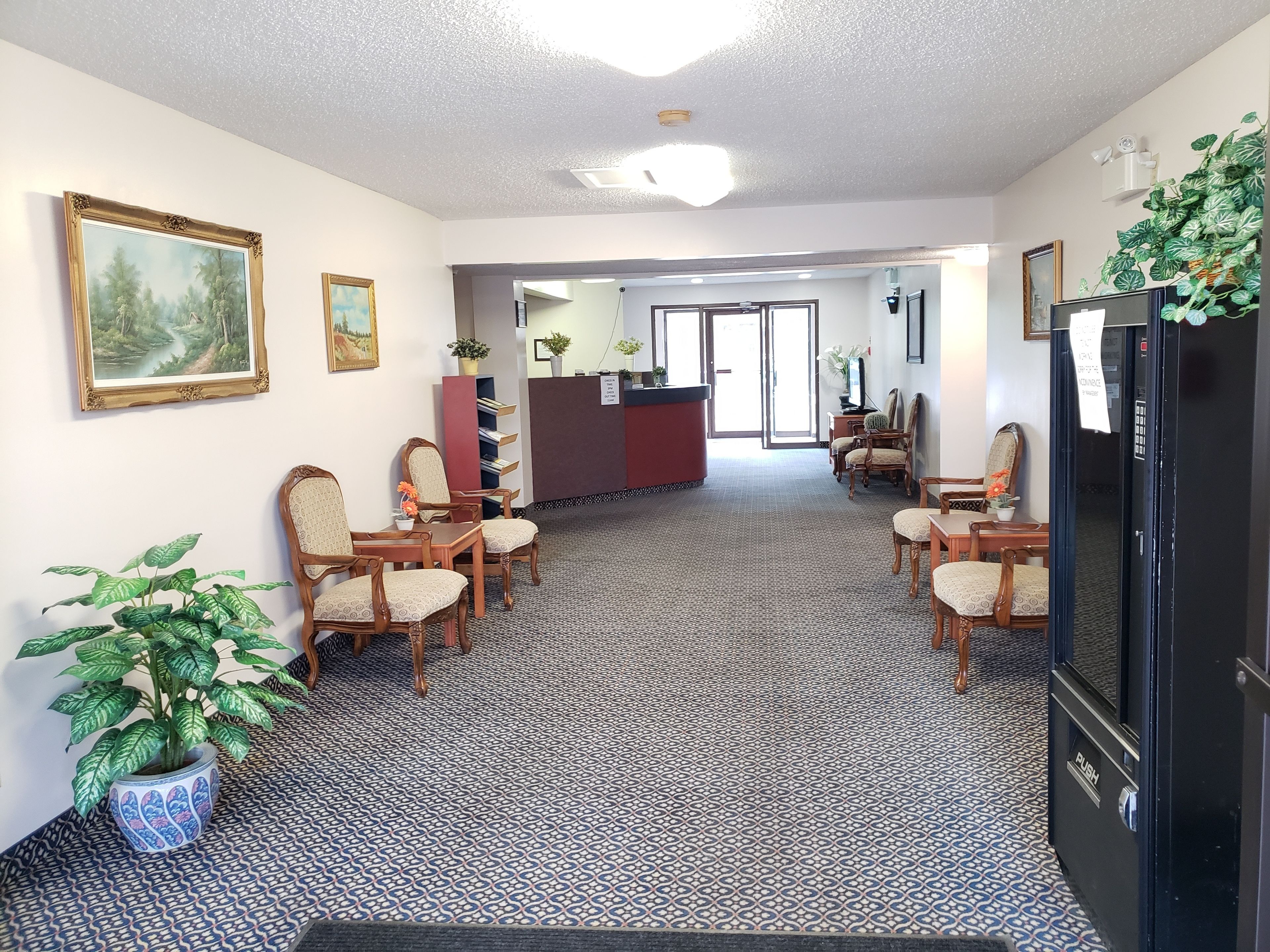 A hotel lobby with a reception desk, seating area, and a patterned carpet.
