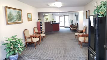 A hotel lobby with a reception desk, seating area, and a patterned carpet.