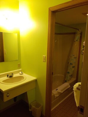 A bathroom with a sink, mirror, and shower.