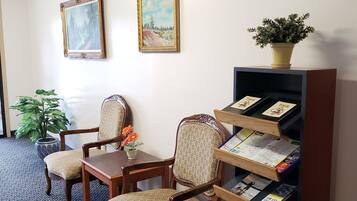 A room with a patterned carpet, wooden furniture, a bookshelf with books, and two framed paintings on the wall.