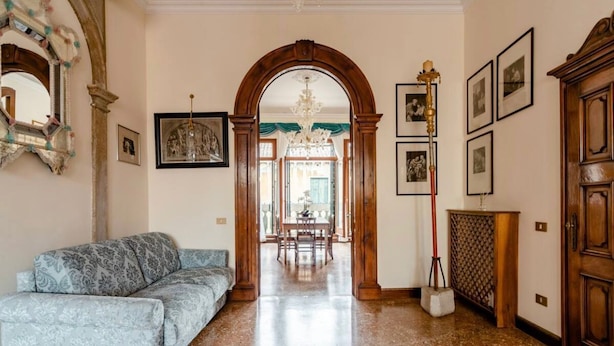 A spacious living area with a sofa, a dining table, and a chandelier. - "LA FENICE" APARTMENT (Venezia)
