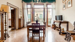 A dining area with a table and chairs, a chandelier, and a view through large windows. - "LA FENICE" APARTMENT (Venezia)