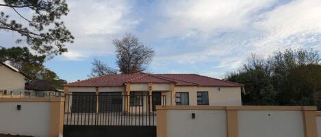 Un lotissement résidentiel fermé, avec une maison dotée d’un toit recouvert de tuiles rouges, de murs de couleur beige et d’une allée en béton.