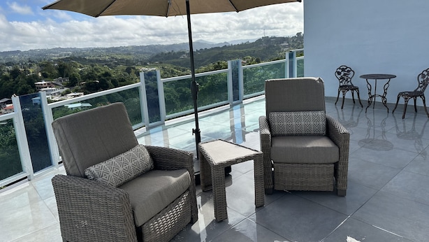 A balcony with wicker furniture, a table, and an umbrella.
