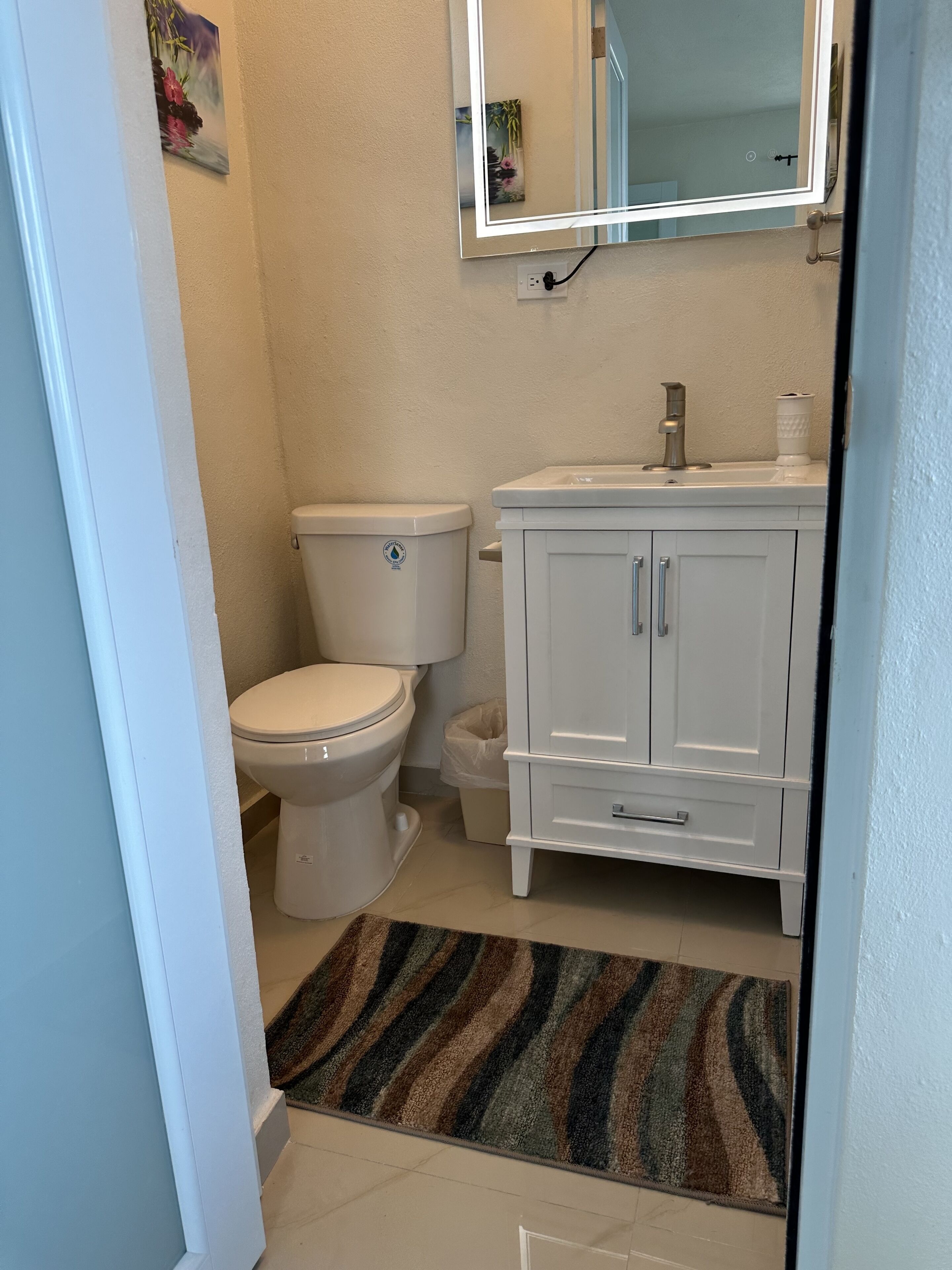 Et badeværelse med toilet, håndvask og skab.