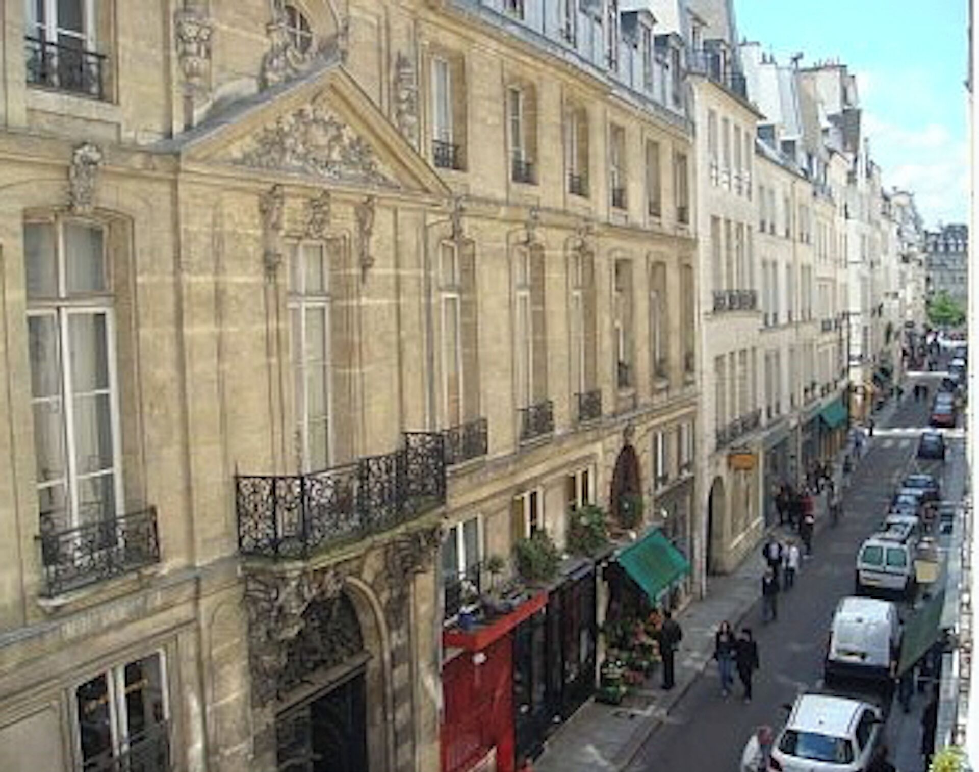 A street view of a historic building with classical architecture, including ornate balconies and detailed stonework.