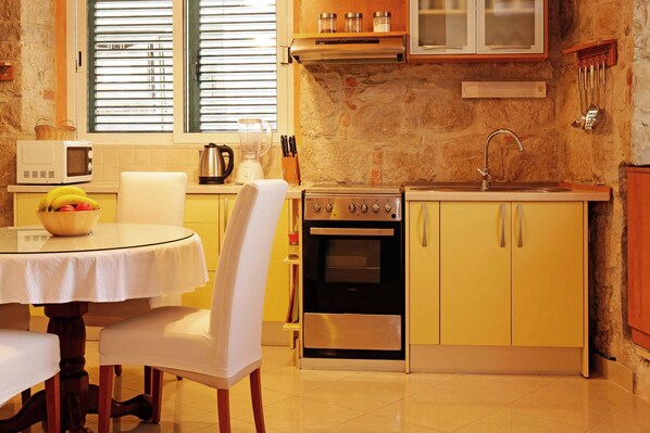 Una cocina compacta equipada con estufa, horno, microondas y una mesa de comedor con sillas.