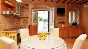 A cozy kitchen with a round table, white chairs, and a bowl of fruit. - All you need studio apartment in Split city center (Split)