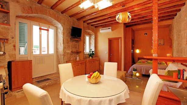 A cozy room with a round table, white chairs, a wooden ceiling, and a bed with a green blanket. - All you need studio apartment in Split city center (Split)