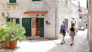 A narrow street with a stone building, green shutters, and a potted plant. - All you need studio apartment in Split city center (Split)