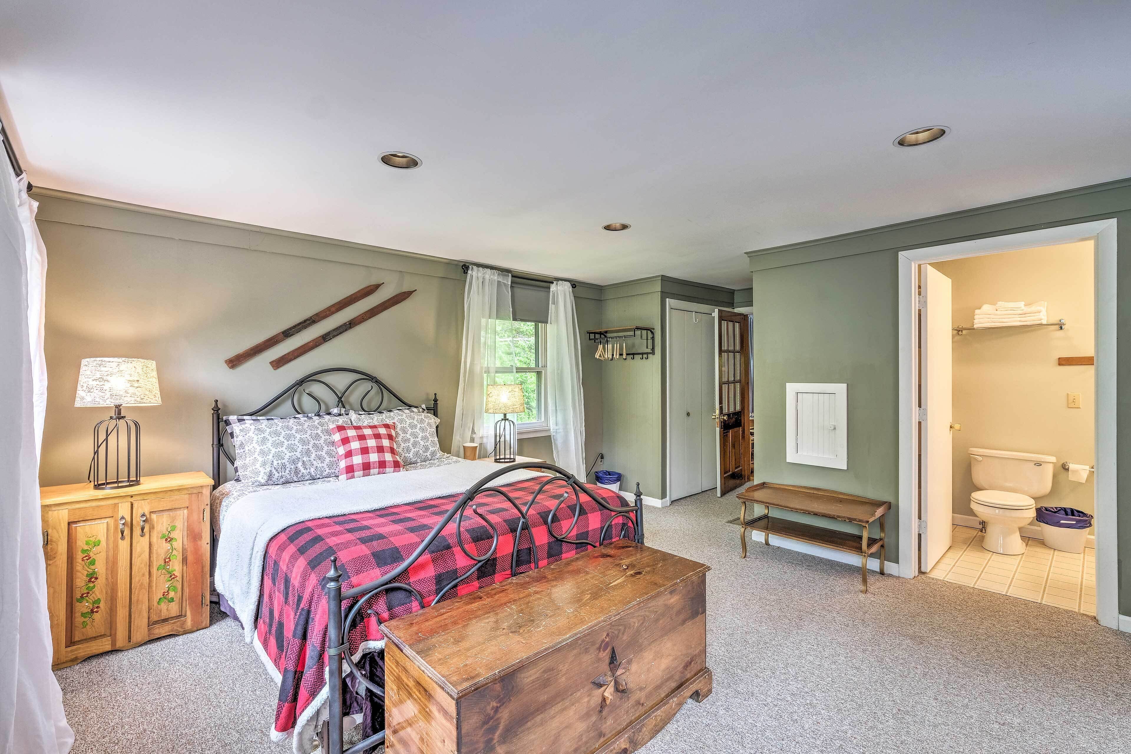 A bedroom with a bed, bedside table, lamp, and a wooden chest of drawers.