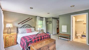 A bedroom with a bed, bedside table, lamp, and a wooden chest of drawers.