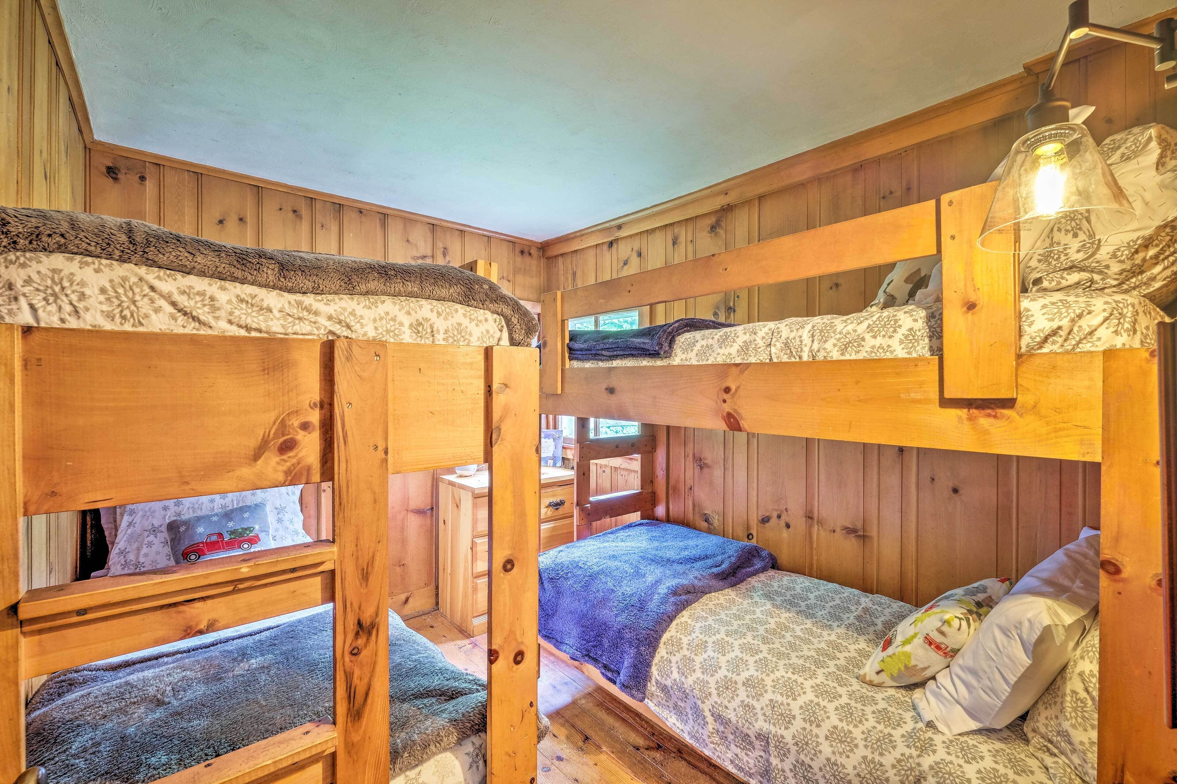 A cozy cabin with bunk beds, wooden walls, a small desk, and a lamp.
