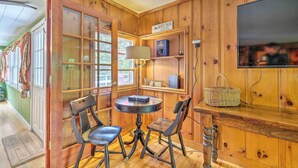 Una habitación con paneles de madera, una mesa redonda y dos sillas, un televisor montado en la pared y un letrero que dice "Mount Snow".
