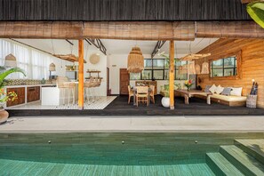 A spacious indoor area with a pool, wooden furniture, and a dining area.