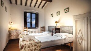 Quarto com duas camas, janela, radiador e guarda-roupa.