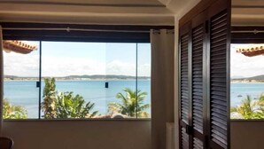 A room with a large window overlooking a body of water, a door, and a chair. - House Residencia (Búzios)
