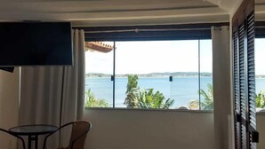 A hotel room with a large window offering a view of the sea and palm trees. - House Residencia (Búzios)