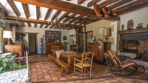 A rustic dining area with a wooden table, benches, and a rocking chair. - Le moulin de la Follaine (Azay-sur-Indre)