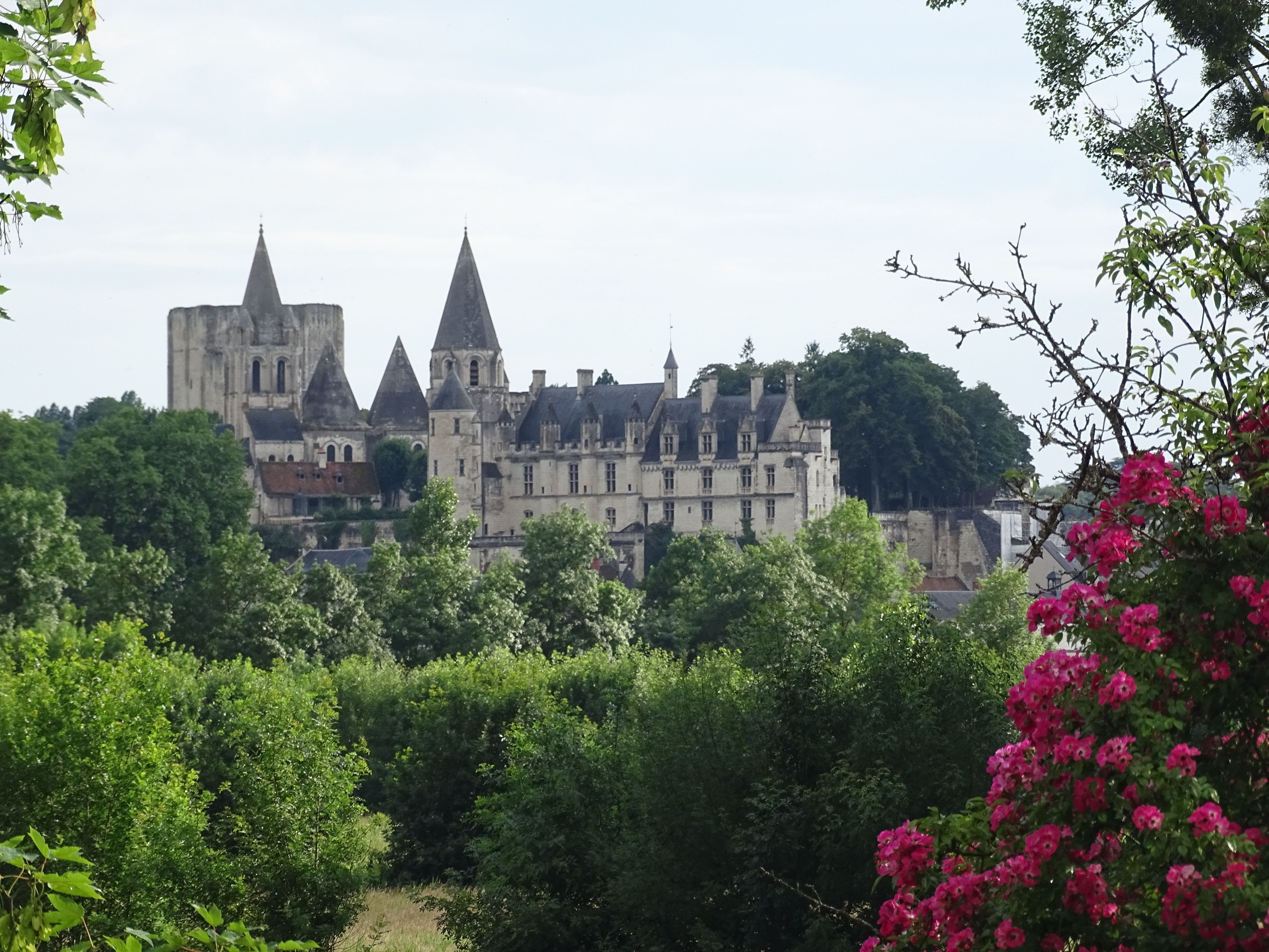 A historic building with multiple towers and a large courtyard surrounded by lush greenery.