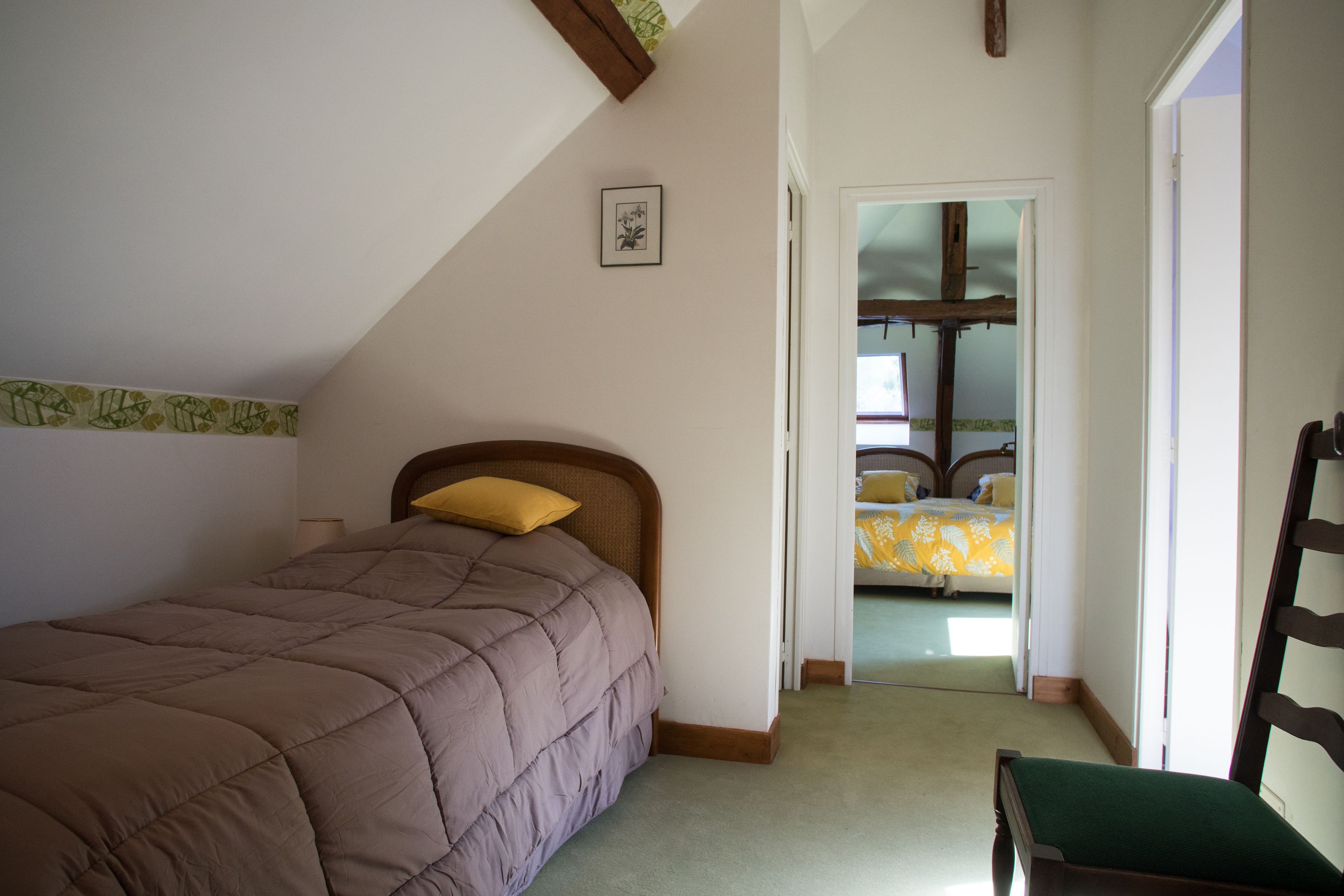Een slaapkamer met een bed, een stoel en een deur naar een andere kamer.