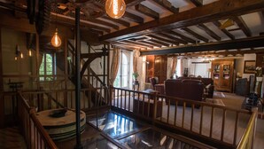 A spacious interior with a wooden staircase, a round table, and a seating area with chairs. - Le moulin de la Follaine (Azay-sur-Indre)