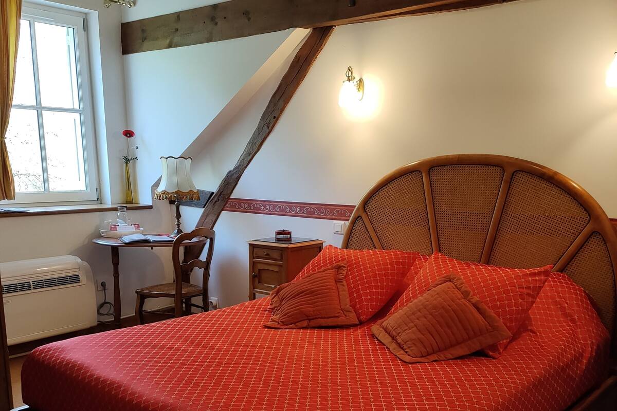 Een slaapkamer met een houten bed, een bureau, een stoel en een raam met gordijnen.