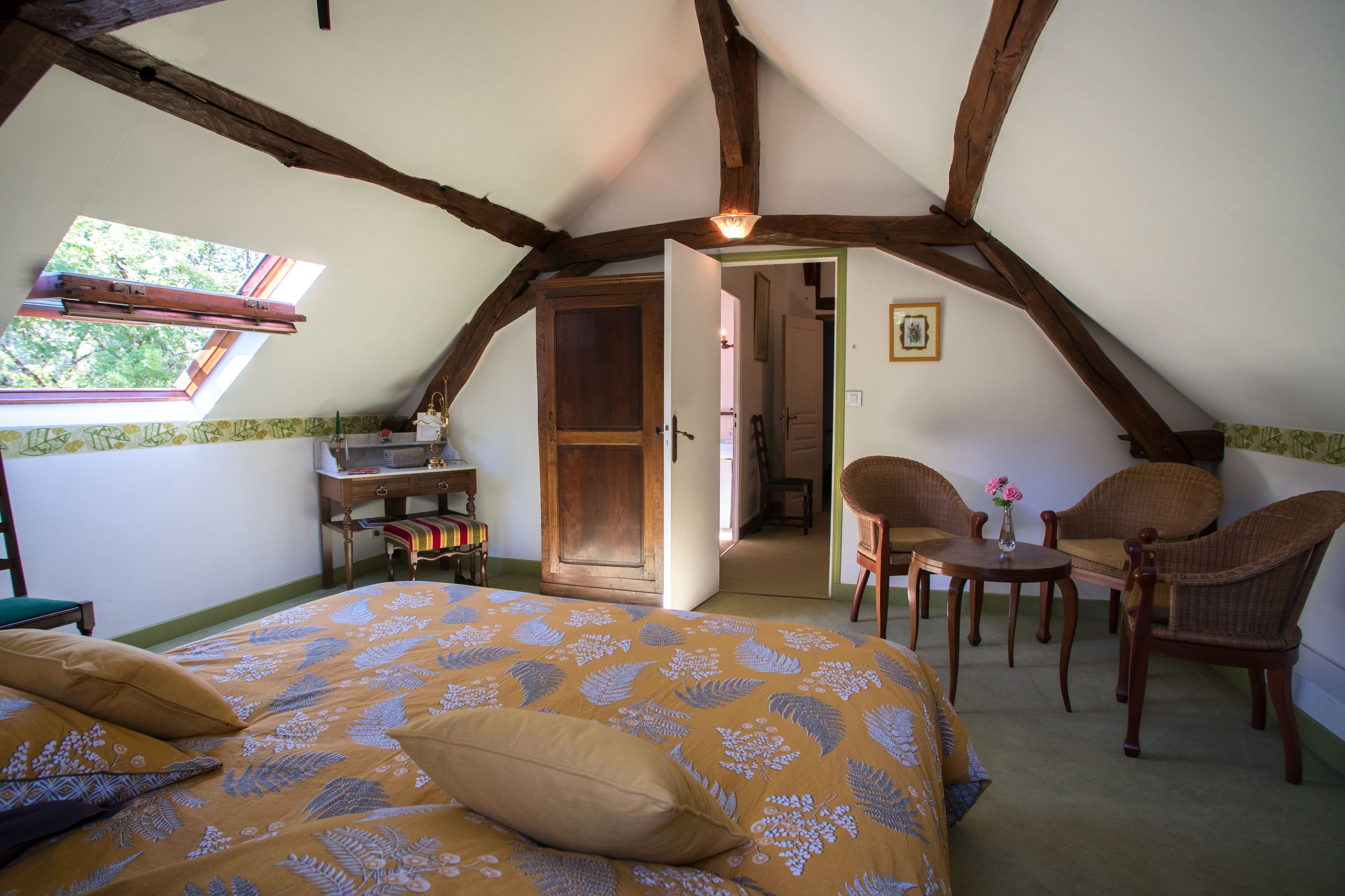 Een slaapkamer met een bed, een bureau en twee rieten stoelen.