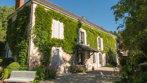A building with ivy-covered walls, a chimney, and a small porch with a bench. - Le moulin de la Follaine (Azay-sur-Indre)