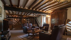 A cozy living room with wooden beams, leather sofas, a coffee table, and a large wooden cabinet. - Le moulin de la Follaine (Azay-sur-Indre)