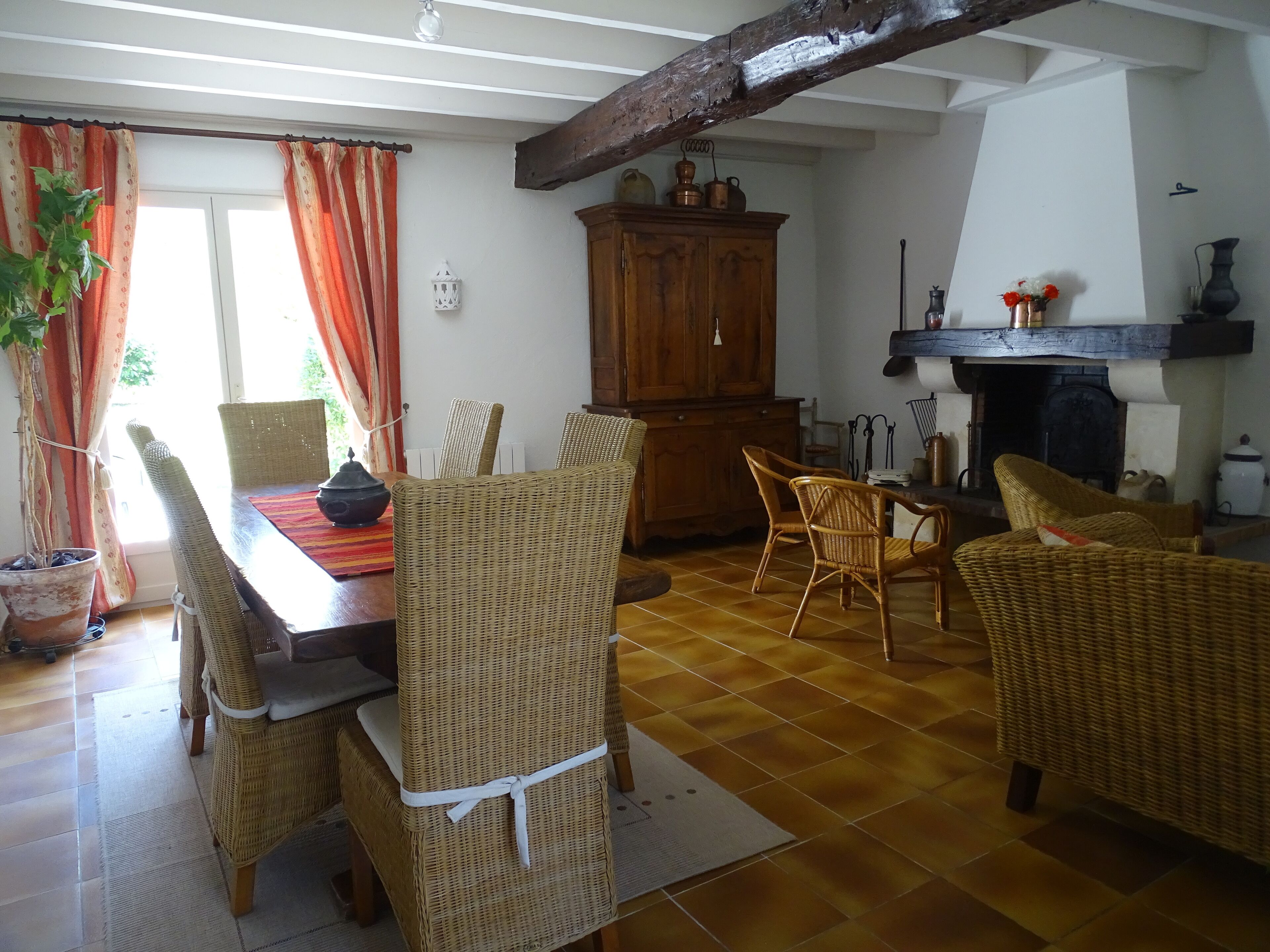 Un comedor con sillas de mimbre, una mesa de madera y una chimenea.