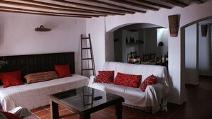 A living room with a sofa and a bed, a glass coffee table, and a wooden ceiling. - Tío Emilio Rural House for 15 people (Bienservida)