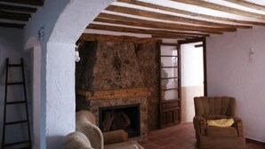 A room with a stone fireplace, wooden beams, a ladder, and a chair. - Tío Emilio Rural House for 15 people (Bienservida)