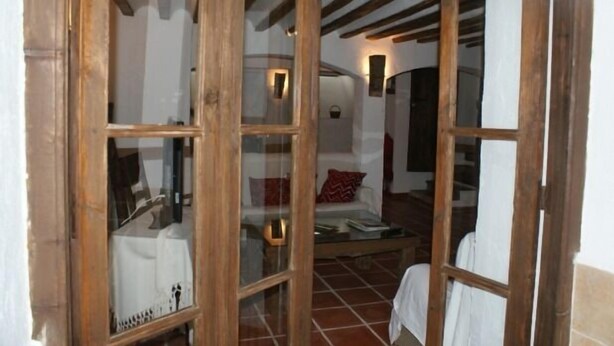 A room with a wooden door, a glass window, a tiled floor, and a sofa with a red pillow. - Tío Emilio Rural House for 15 people (Bienservida)