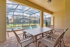 A covered patio area with a glass enclosure, a pool, and a table with chairs. - 6BR Solterra Pool Home | Jacuzzi, Game Room, BBQ & Dog Friendly (Davenport)