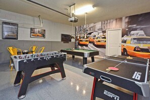 Une pièce équipée d’un baby-foot, d’une table de billard et d’une table de ping-pong.