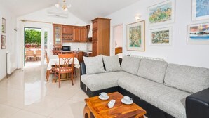 A modern living room with a grey sofa, wooden coffee table, and a dining area with a table and chairs. - Villa Agape - Three Bedroom Villa with Swimming Pool (Mirca)