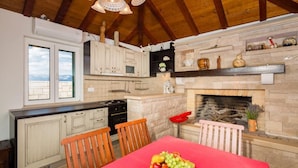 A kitchen with wooden beams, a stone fireplace, and a dining table with fruit. - Villa Agape - Three Bedroom Villa with Swimming Pool (Mirca)