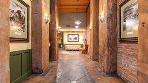 A hallway with wooden columns, framed pictures, a seating area with a sofa and chairs, and a patterned floor. - Modern Studio in the Heart of the City II (Seattle)