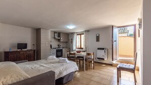A bedroom with a bed, a desk, and a kitchenette. - Casa Erika, relax in Tuscany   (Partino)