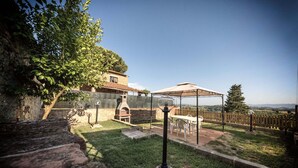 A backyard with a stone wall, a barbecue grill, a pergola, and a view of the countryside. - Casa Erika, relax in Tuscany   (Partino)